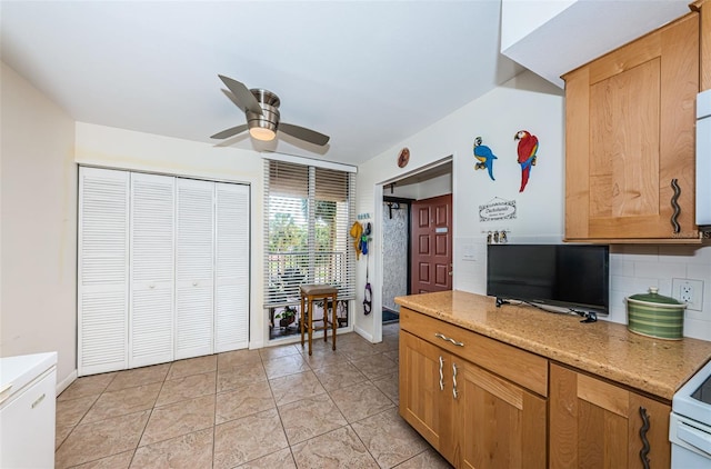 kitchen featuring backsplash, ceiling fan, light tile patterned floors, and light stone counters