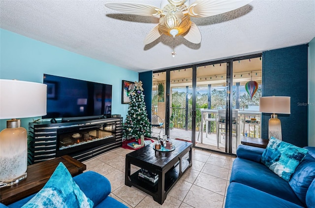 living room with tile patterned floors, ceiling fan, expansive windows, and a textured ceiling