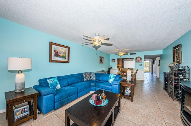 living room featuring ceiling fan, light tile patterned flooring, and a textured ceiling