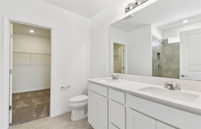 bathroom with tile patterned floors, toilet, vanity, and a tile shower