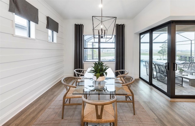 dining area featuring a healthy amount of sunlight, wood-type flooring, and a chandelier