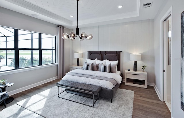 bedroom with a raised ceiling, a chandelier, dark hardwood / wood-style floors, and ornamental molding