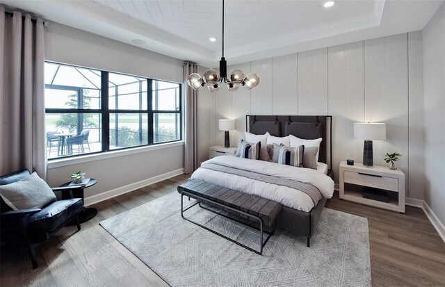 bedroom featuring ornamental molding, dark hardwood / wood-style flooring, a raised ceiling, and a notable chandelier