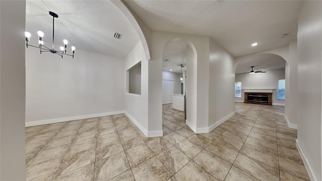 interior space featuring ceiling fan with notable chandelier and a textured ceiling