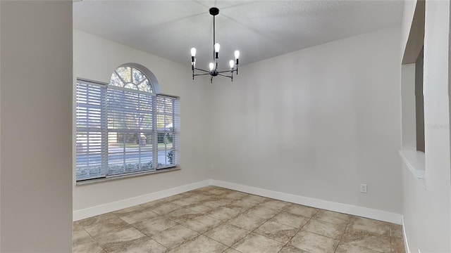 unfurnished room with a notable chandelier