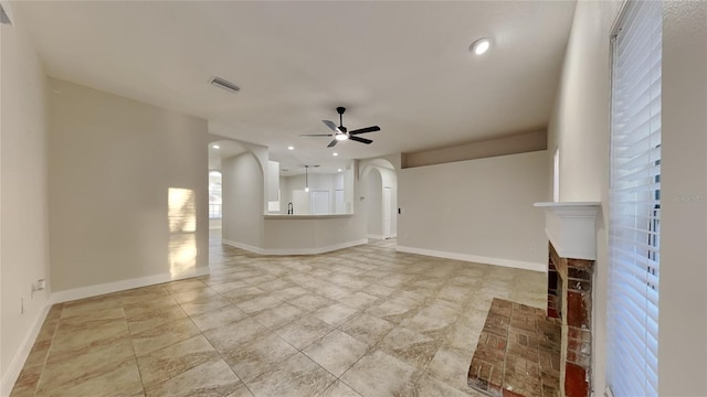 unfurnished living room with ceiling fan and a fireplace