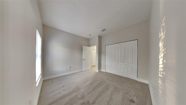 unfurnished bedroom featuring multiple windows, a closet, and carpet