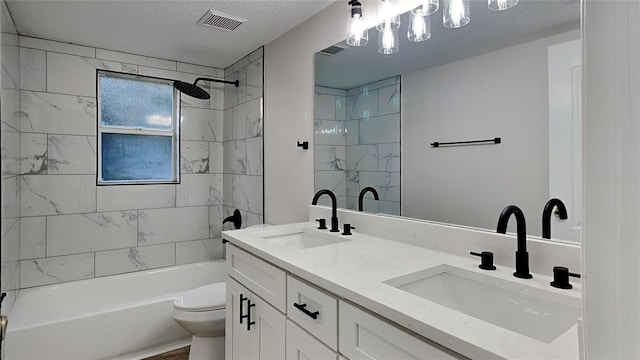 full bathroom featuring vanity, tiled shower / bath combo, a textured ceiling, and toilet