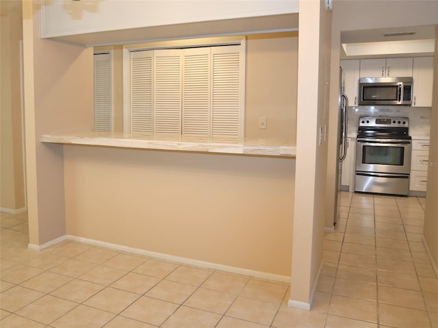 kitchen with stainless steel appliances, light tile patterned floors, and kitchen peninsula