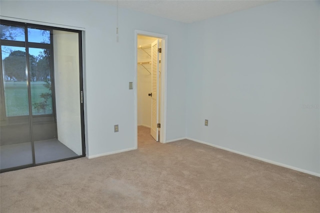 unfurnished bedroom featuring a walk in closet, a closet, and light carpet