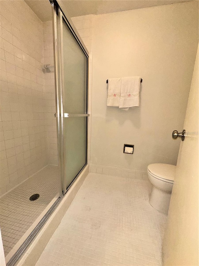 bathroom featuring toilet, tile patterned floors, and walk in shower