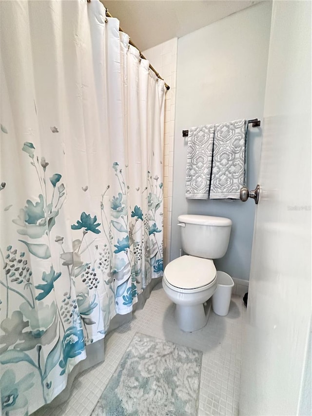 bathroom featuring toilet, tile patterned floors, and a shower with curtain