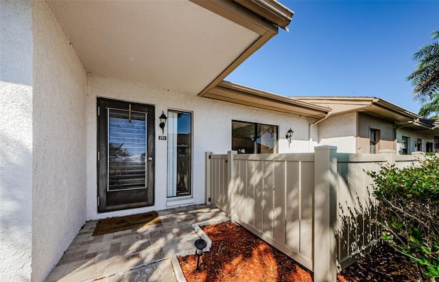 property entrance featuring fence and stucco siding