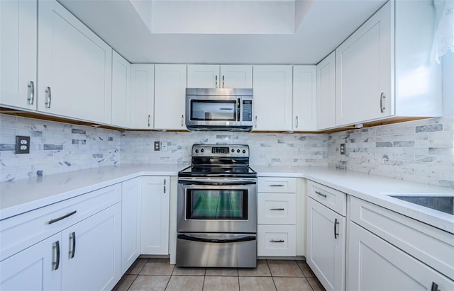 kitchen featuring backsplash, stainless steel appliances, white cabinets, light countertops, and light tile patterned floors