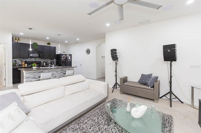 carpeted living room featuring ceiling fan and sink