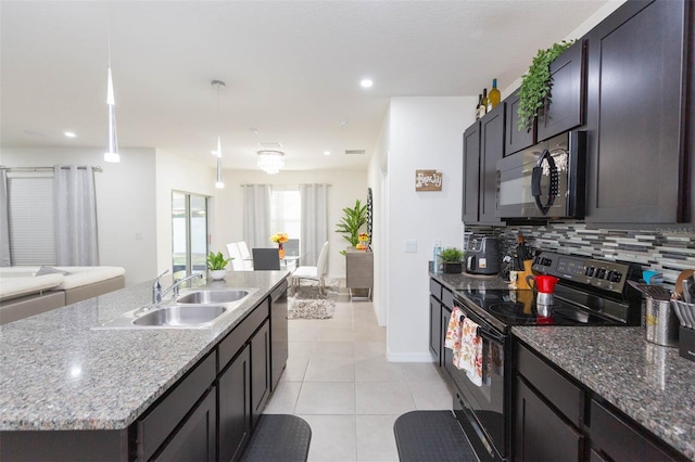 kitchen featuring appliances with stainless steel finishes, backsplash, sink, pendant lighting, and an island with sink