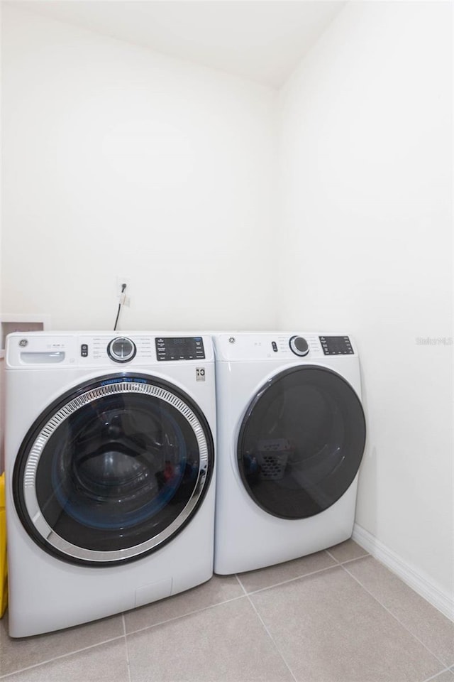 clothes washing area featuring light tile patterned floors and independent washer and dryer