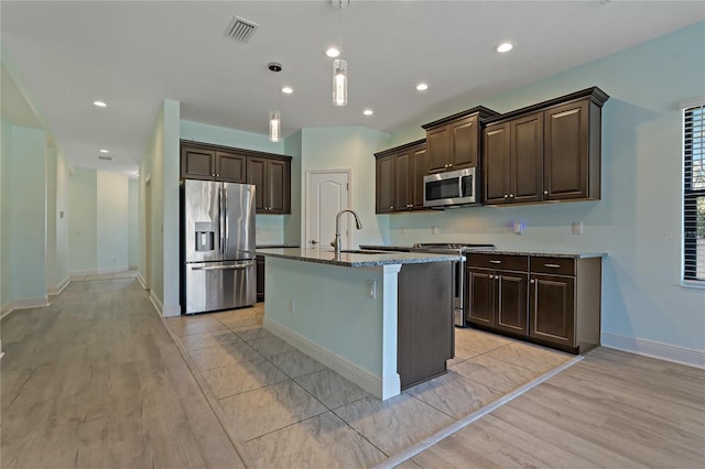13584 Old Creek Ct, Parrish, FL 34219 - kitchen with appliances with stainless steel finishes, a sink, dark brown cabinets, light wood-style floors, and dark stone countertops