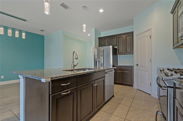 13584 Old Creek Ct, Parrish, FL 34219 - kitchen with stainless steel appliances, a sink, dark brown cabinetry, a kitchen island with sink, and light stone counters