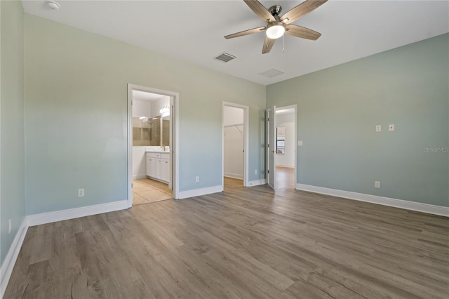 13584 Old Creek Ct, Parrish, FL 34219 - unfurnished bedroom with a walk in closet, wood finished floors, baseboards, a closet, and connected bathroom