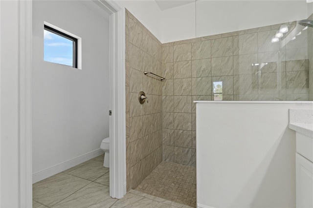 bathroom featuring a tile shower, vanity, and toilet