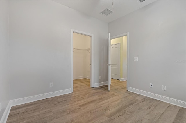 unfurnished bedroom featuring light hardwood / wood-style floors, a spacious closet, and a closet