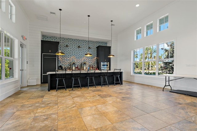 13584 Old Creek Ct, Parrish, FL 34219 - kitchen with an accent wall, a breakfast bar, baseboards, dark cabinets, and ornamental molding