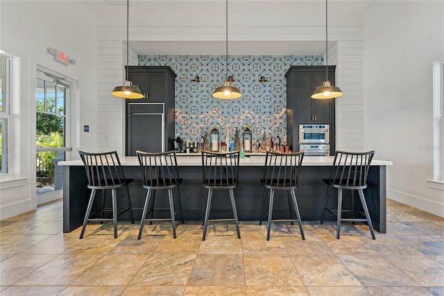 13584 Old Creek Ct, Parrish, FL 34219 - kitchen with light countertops, baseboards, paneled fridge, an accent wall, and pendant lighting