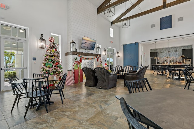 dining space featuring a barn door, beamed ceiling, and high vaulted ceiling