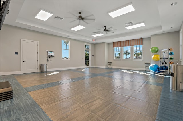 exercise area featuring a raised ceiling and ceiling fan