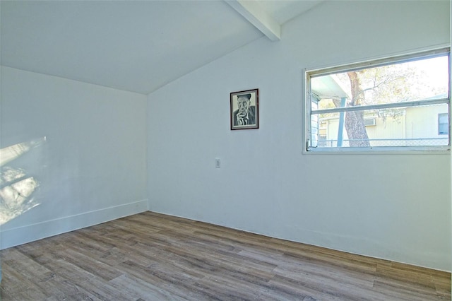 spare room with hardwood / wood-style floors and lofted ceiling with beams