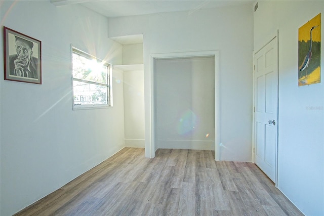 unfurnished bedroom with light wood-type flooring and a closet