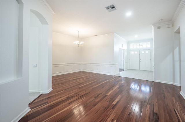 spare room with crown molding, a chandelier, and dark hardwood / wood-style floors