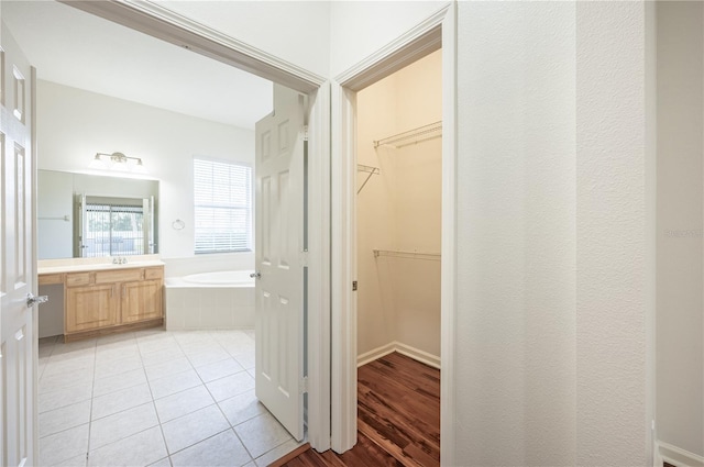 bathroom with tile patterned flooring, vanity, and tiled tub