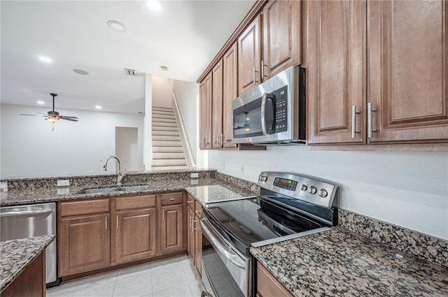 kitchen featuring appliances with stainless steel finishes, dark stone counters, ceiling fan, sink, and light tile patterned floors