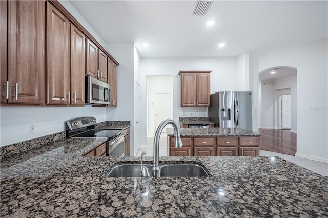 kitchen with dark stone counters, sink, hardwood / wood-style floors, and stainless steel appliances