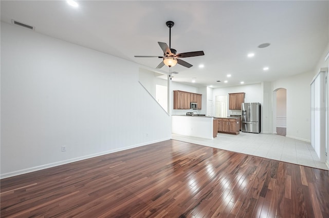 unfurnished living room featuring ceiling fan and light wood-type flooring