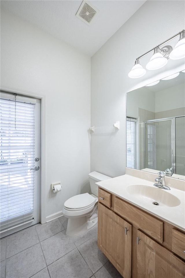 bathroom featuring tile patterned flooring, vanity, toilet, and a shower with door