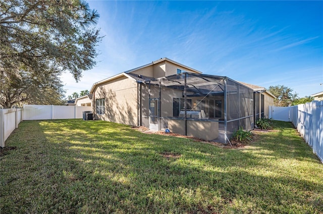 back of house with central AC unit, a lanai, and a yard