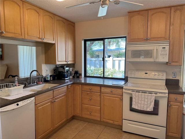 kitchen featuring a textured ceiling, light tile patterned flooring, white appliances, and sink