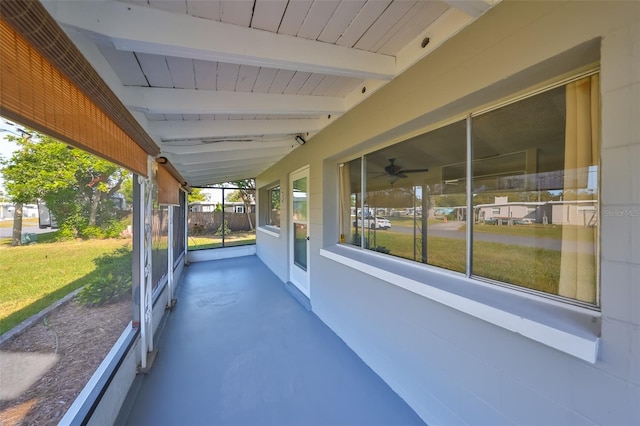 unfurnished sunroom featuring vaulted ceiling with beams and ceiling fan