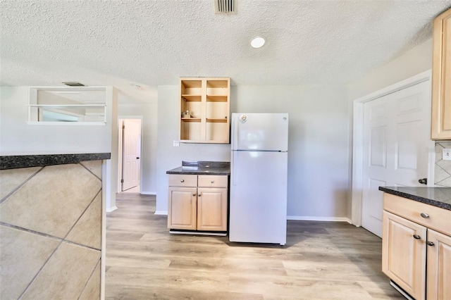 kitchen with white refrigerator, a textured ceiling, and light hardwood / wood-style flooring