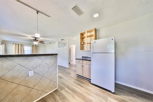 kitchen with ceiling fan, white refrigerator, a textured ceiling, and light hardwood / wood-style flooring