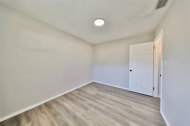 unfurnished room featuring light hardwood / wood-style floors and a textured ceiling