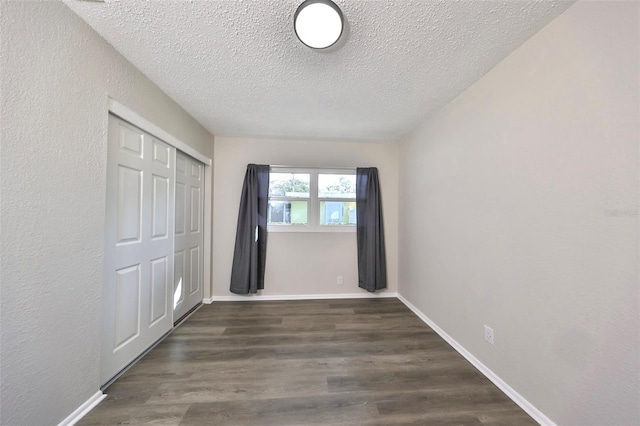 unfurnished bedroom with a textured ceiling, a closet, and dark wood-type flooring