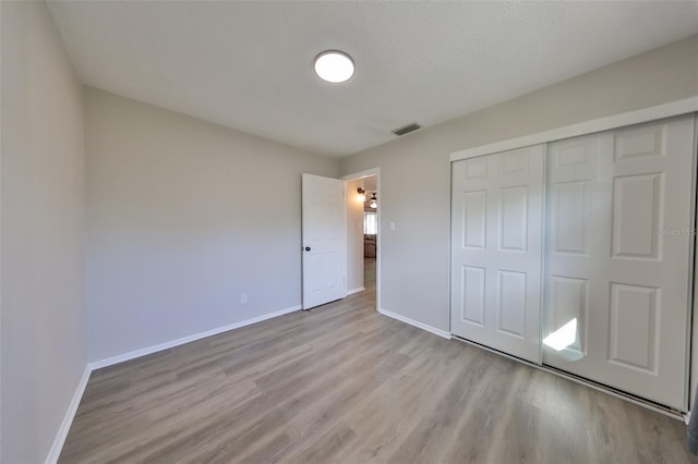 unfurnished bedroom featuring a closet, a textured ceiling, and light hardwood / wood-style flooring