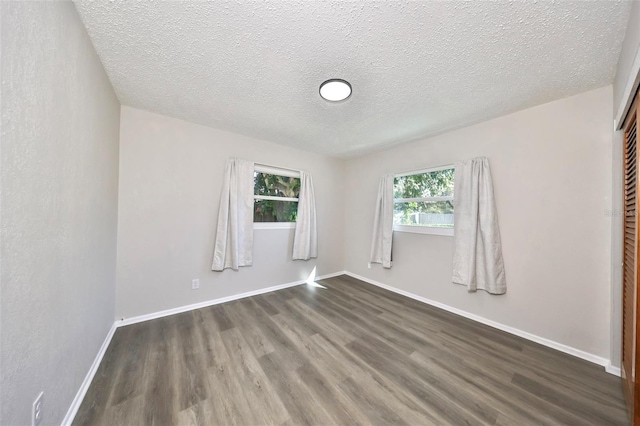 empty room featuring dark hardwood / wood-style flooring and a textured ceiling