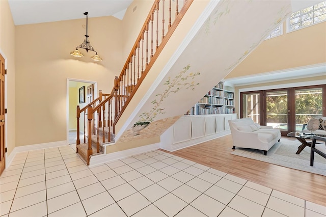 entryway with light hardwood / wood-style floors, high vaulted ceiling, and french doors