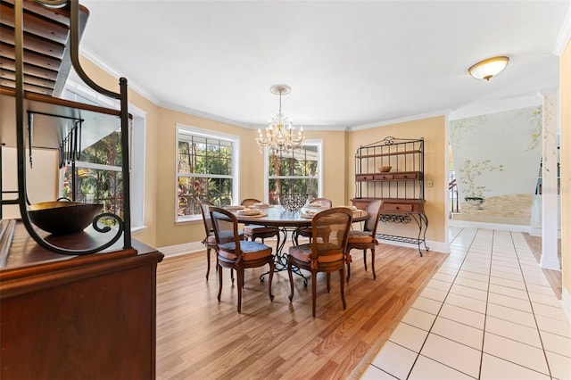 dining area with an inviting chandelier, ornamental molding, and light wood-type flooring