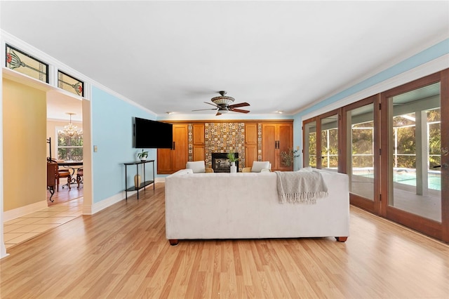 living room featuring ceiling fan with notable chandelier, ornamental molding, and light hardwood / wood-style flooring